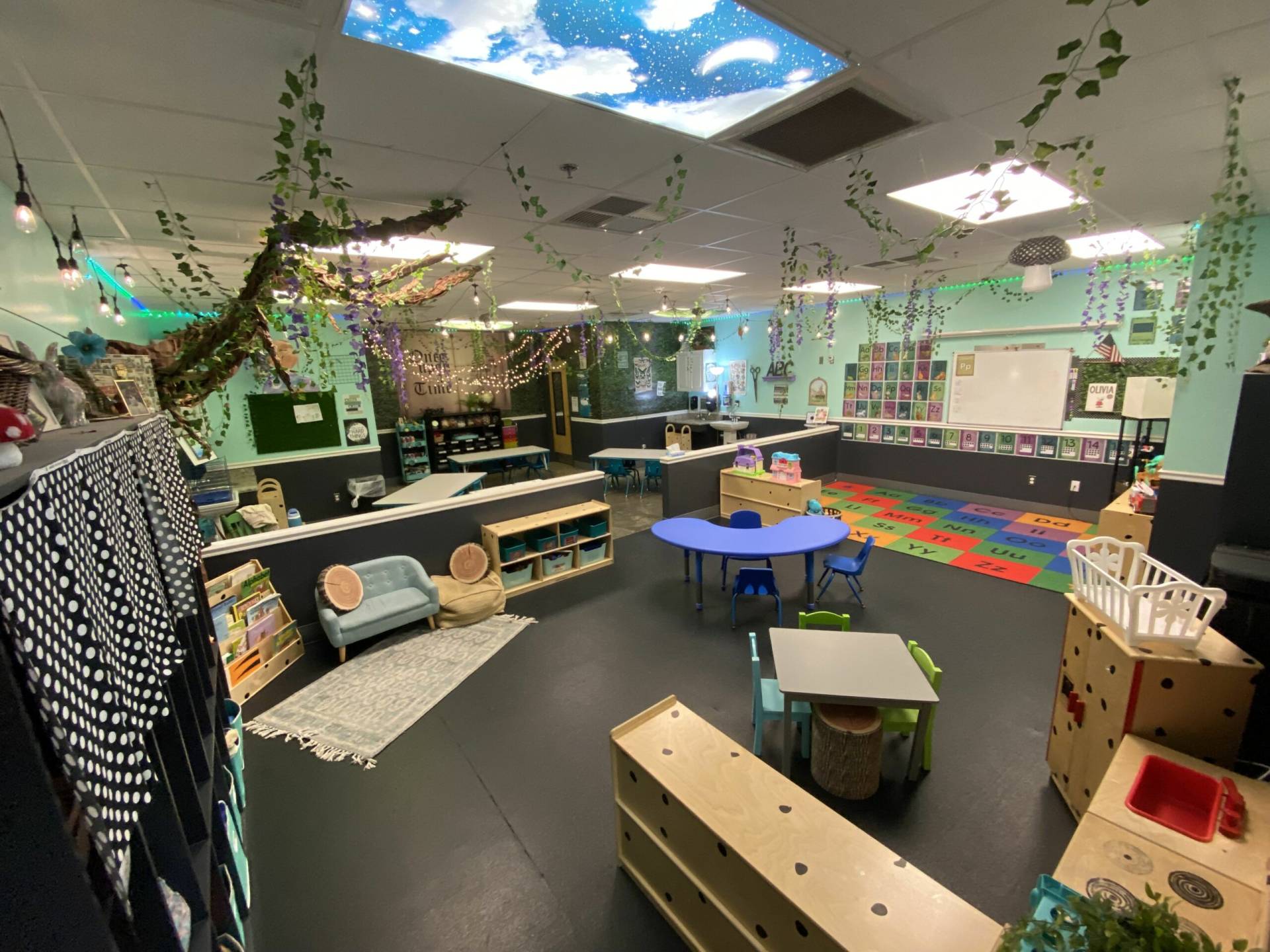 A bright preschool classroom at In The Zone with natural light, learning centers and soft seating