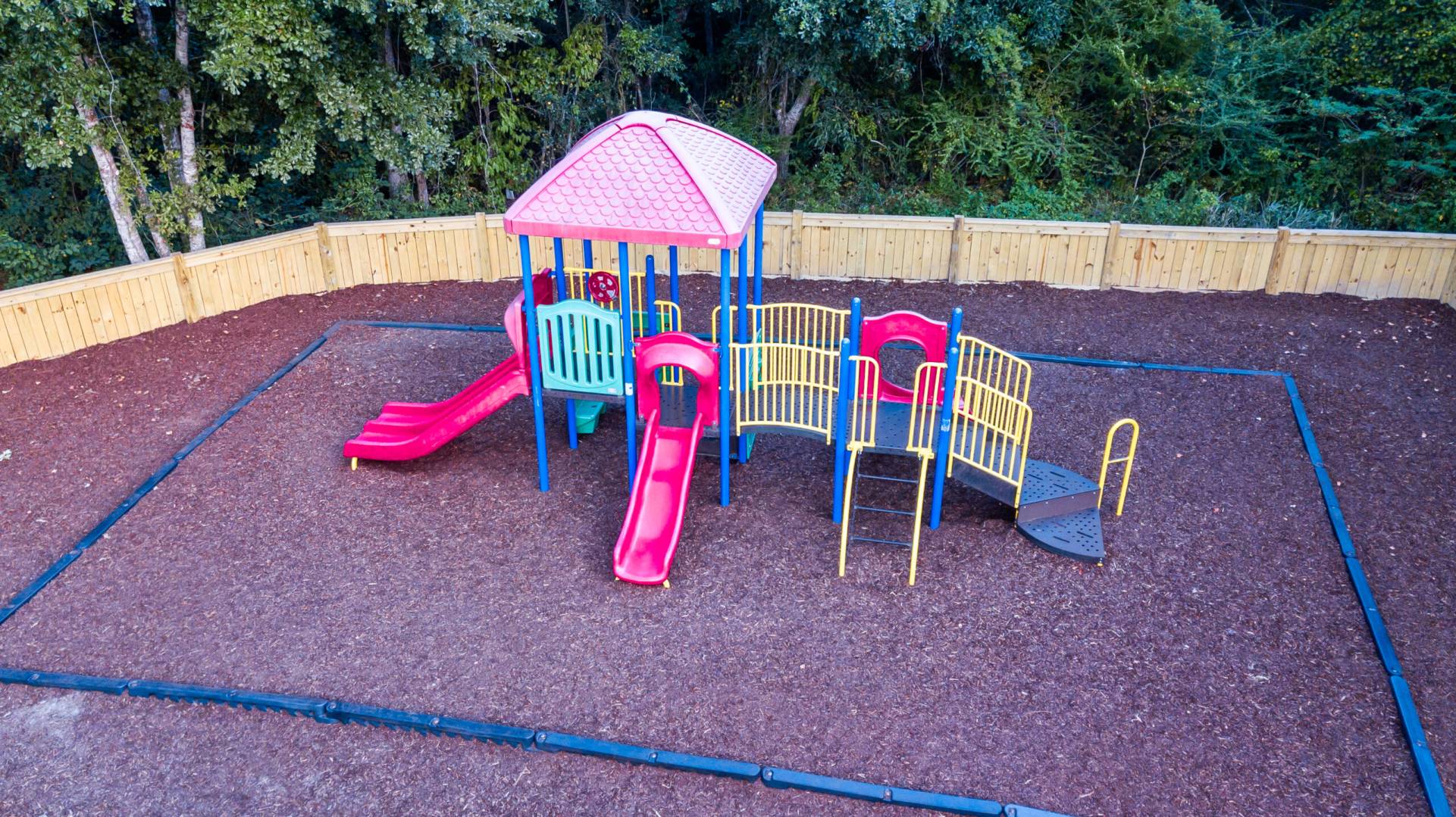 A playground structure with slides on a soft safety surface